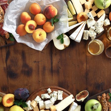 Meze şarap cam beyaz şarap ile bir masa. Çeşitli şarap atıştırmalıklar çerçevesinde: üzüm, şeftali, kayısı, armut, elma, jamon, sert peynir, brie peyniri ve Rokfor peyniri ahşap masa üstten görünüm üzerinde düz lay