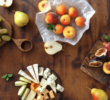 Şarap için meze tablo. Çeşitli aperatifler şarap: üzüm, şeftali, kayısı, armut, elma, jamon, sert peynir, brie peyniri ve Rokfor peyniri ahşap masa üstten görünüm üzerinde düz lay