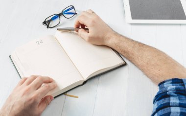 Adam ahşap masa üstünde belgili tanımlık defter için yazma notlar eller