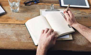 Adam evde ahşap masa üzerinde not defterleri yazma