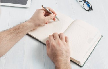 Adam evde ahşap masa üzerinde not defterleri yazma