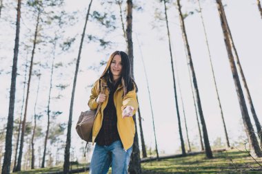 Sırt çantası olan kadın el verir