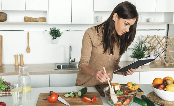 Cooking healthy food in home kitchen concept. Beautiful young woman preparing summer salad