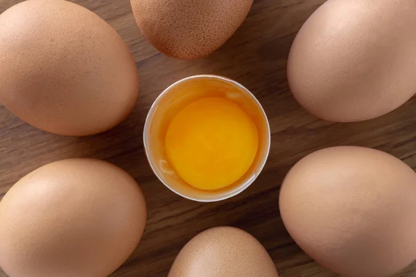 木製の背景トップビュー上の全卵と壊れた茶色の生の卵 — ストック写真