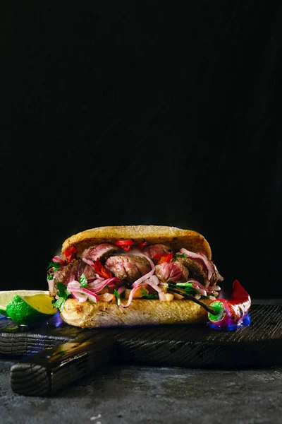Grilled spicy steak sandwiches steak in fire flame on wooden cutting boards on dark background close up