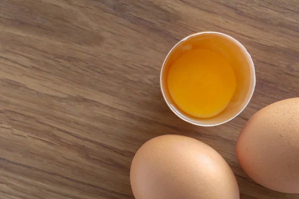 Gebroken bruin rauwe ei hele eieren houten achtergrond top uitzicht — Stockfoto