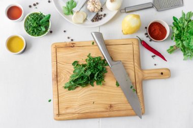 Beyaz ahşap masa üstü görünümünde yeşil Chimichurri veya Chimmichurri salsa veya sos pişirmek için ham maddeler