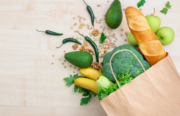 Bag food concept. Groceries shopping paper bag with healthy food on a wooden background top view