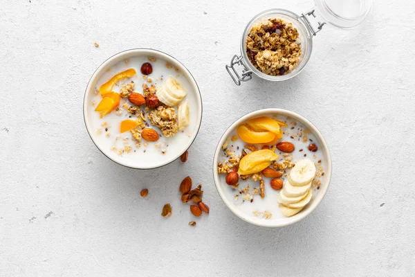 Granola bowl with fruits, nuts, milk and peanut butter in bowl on a white background. Healthy breakfast cereal top view