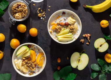 Beyaz bir arka plan üzerinde kase meyve, fındık, süt ve fıstık ezmesi ile Granola kahvaltı. Sağlıklı kahvaltılık gevrek üst görünümü 