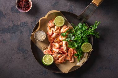 Koyu bir arka plan üst görünümünde yemek pişirmek için malzemelerle bir tavada Ham karides