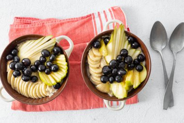 Yulaf ezmesi ve armut, elma, yaban mersini, muz beyaz bir arka plan üst görünümünde plaka. Kahvaltı sofrası konsepti