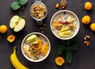 Beyaz arka planda meyve, fındık, süt ve fıstık ezmeli granola kasesi. Sağlıklı kahvaltı gevreği üst görünümü