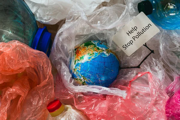 Save our planet or World Environment Day concept Earth in plastic bags holds card with the inscription help