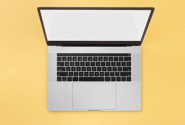 Open laptop with blank screen on a yellow background top view