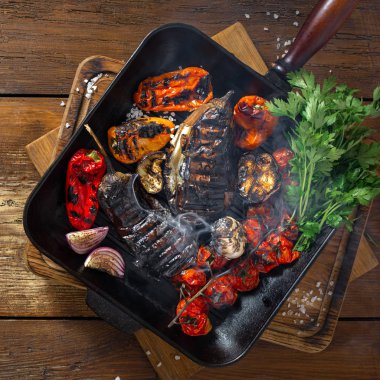 Ahşap arka plan üst görünümünde ızgara tavada pişirilen çeşitli sebzeler