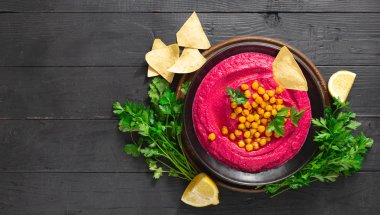 Koyu arka plan üst görünümünde bir tabak ta pancar humus