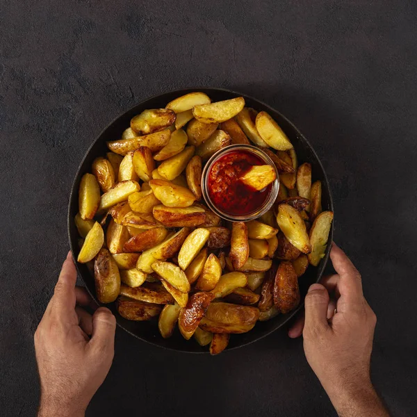 Male hands holding a pan with fresh fried potatoes