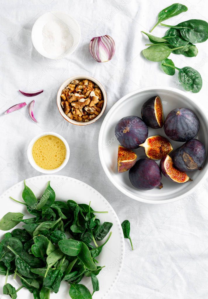 Raw ingredients for cooking vegetarian salad of figs, nuts and spinach top view