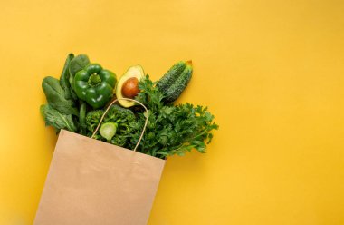 Kağıt torba tam yeşil taze sebze sarı arka plan üst görünüm düz yatıyordu