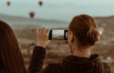 Kapadokya, Türkiye 'de hava balonlarıyla güzel bir manzaranın fotoğrafını çeken kadın