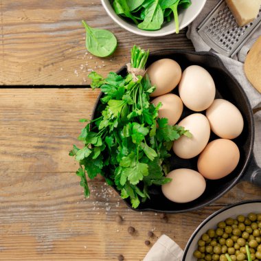 Yemek pişirmek için malzeme ile sağlıklı kahvaltı masası. bezelye, yumurta, ıspanak, maydanoz ve peynir ahşap arka plan üst görünüm kopya alanı