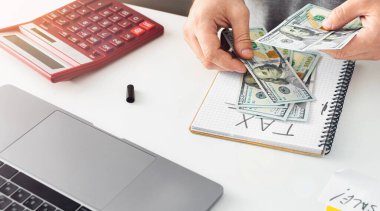 Vergi günü konsepti. İş adamı vergiler için para sayar.