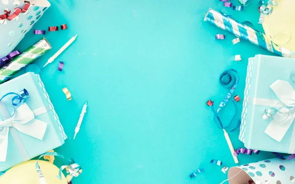 Celebrazione sfondo con stelle filanti partito colorato, coriandoli e cappelli festa di compleanno su blu bacground vista dall'alto — Foto Stock