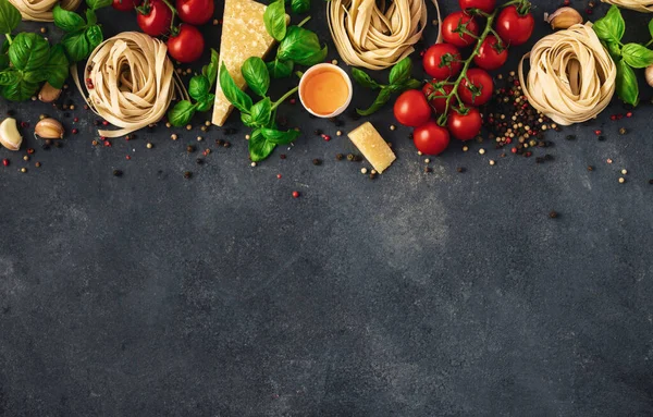 Iettuccine with ingredients for cooking Italian pasta on dark background, top view