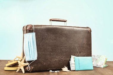 İyi yolculuklar. İçinde pasaport, seyahat aksesuarları ve tıbbi maske olan eski çanta. Seyahat ederken maske rejiminin gözetimi