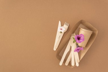Kalıp sıfır atık, plastik içermeyen konsept. Tek kullanımlık kağıt bardaklar ve tahta çatallar ve bej arka planda fotokopi alanı olan bıçaklar.