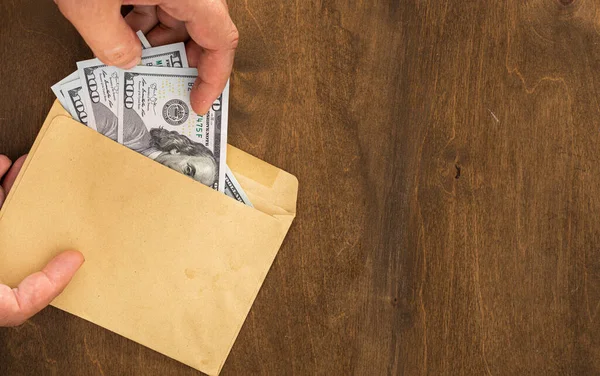 Mężczyzna ręka bierze pieniądze z papierowej koperty łapówki lub korupcji pieniądze koncepcja — Zdjęcie stockowe