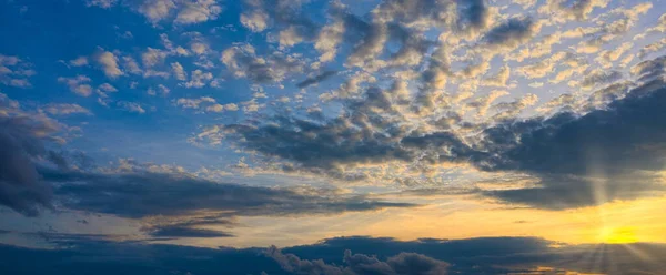 Panorama shining of the sun through the beautiful clouds of the setting sun