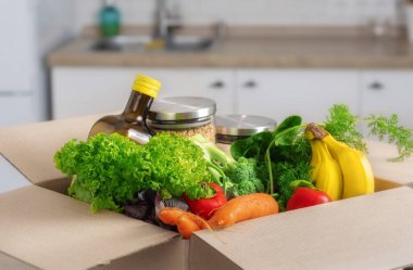 Ev mutfağında içi yiyecek dolu karton kutu açıldı. Güvenli teslimat konseri