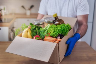 Güvenli teslimat konseri. Karton kutular taşıyan teslimatçı. Mutfakta yiyecek var.