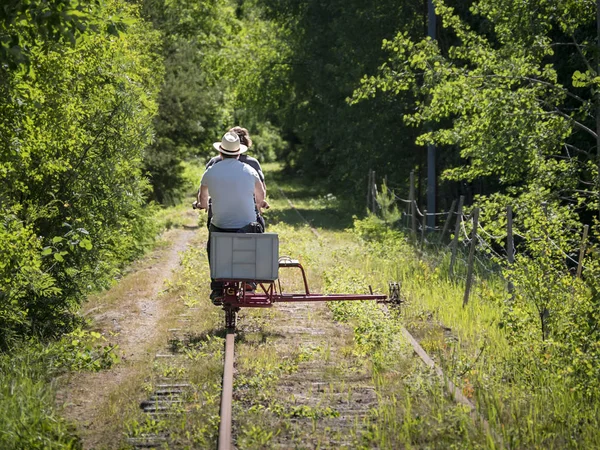 Two people riding a rail-cycle draisine through the countryside in Delsbo, Sweden