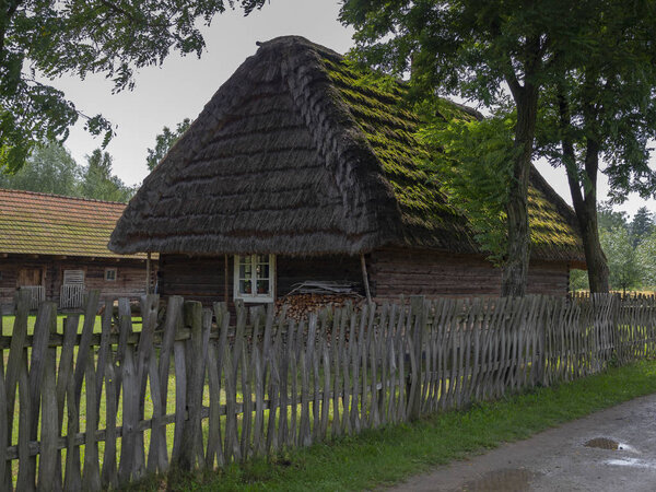 Old wooden thatched cottages in the open-air Folk Museum of Kolbuszowa, Poland in summer