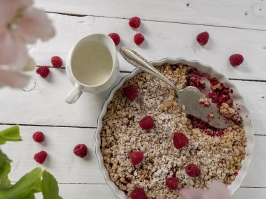 Raspberry cake with crumble with vanilla sauce in a round form