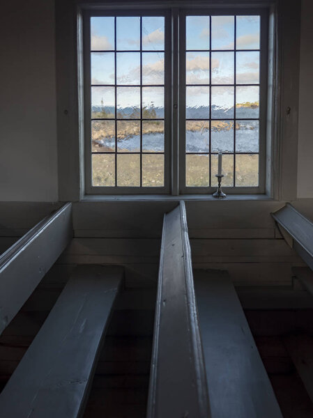 Interior of a Protestant chapel with white walls and candlesticks in the windows