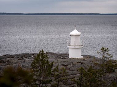 Bulutlu havalarda kayalık sahilde Beyaz deniz feneri