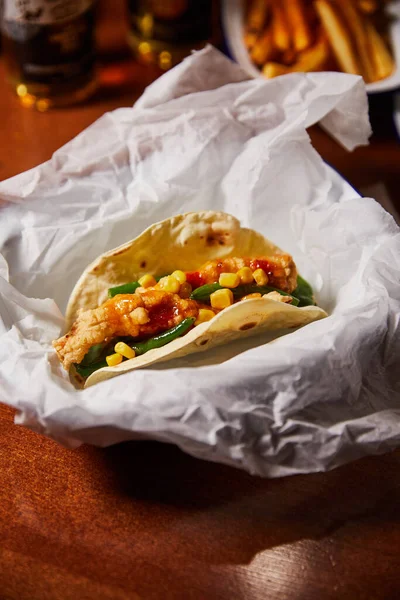 food wrapping paper with mexican burrito on wooden table, close view