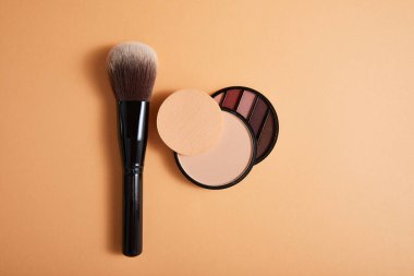 Profesyonel makyaj fırçası ve bej arka planda göz farı olan toz, yakın görüş, güzellik konsepti 