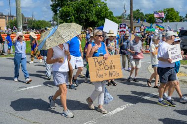 New Orleans, LA, ABD - 14 Haziran 2025: Marigny Mahallesi 'nde Krallar Günü Geçidi' nde işaretleri, şemsiyeleri ve bayrakları olan Trump karşıtı göstericiler yürüyüş