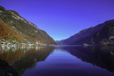 Güzel sonbahar sabahı görünümü mavi gökyüzü, tarihi kilise ve yapraklara dağlarla Hallstatt Gölü 