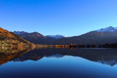 Kapalı üst kısmındaki dağlar Zell am güzel göster kristal berraklığında su Gölü ve kar görmek Avusturya'da sırasında geç düşmek