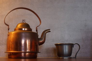 Bakır bir su ısıtıcısı ve bir kupa çimento duvar arka planı hazır.