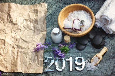 Spa ayarlanır için 2019 banyo tuzu ve beyaz losyon, yordam, siyah taşlar orada soldaki sıcak bir masaj için hazırlanan havlu ile Kraft kağıt, metniniz için.
