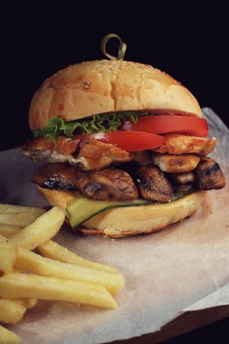 Tavuk göğsü ve siyah arka plan üzerine mantarlı burger.