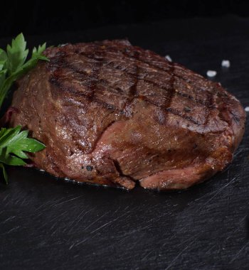 Dana madalyon biftek siyah bir zemin üzerine.