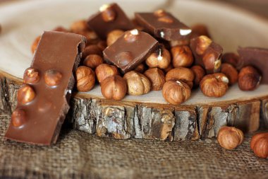 Bir avuç fındık yanında fındık ile sütlü çikolata parçasına.